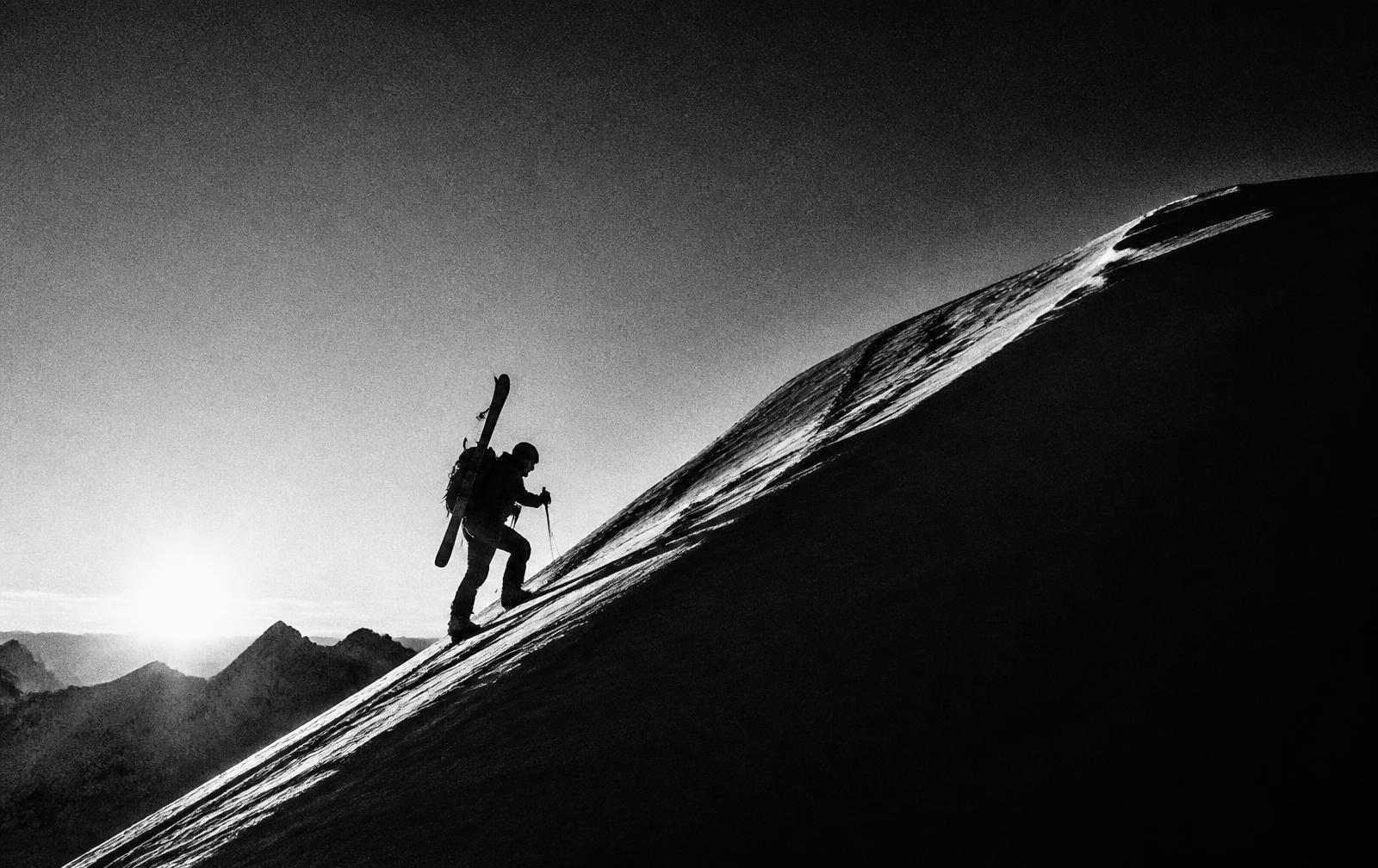 Ski mountaineer climbing a ridge at sunrise